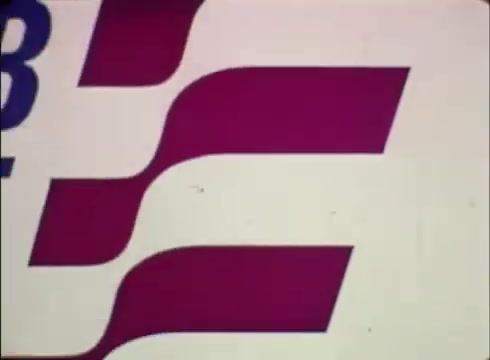 The still from 'Job Service Nebraska - Book Store' features a graphic design with bold, wavy lines in red and white, likely representing movement or dynamism. The text element, presumably the title or logo, is prominently displayed in a simple, clear font, reflecting a professional and approachable image. This visual suggests a focus on employment services and resource accessibility, typical of job placement and assistance programs. The 16mm print gives it a vintage feel, indicative of the era in which the commercial was produced.