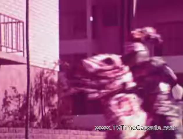 The 16mm still from the 'Lady Scott' commercials features a vibrant and playful scene, likely intended to showcase the product's fun and colorful aspects. The image captures a dynamic moment, possibly related to a performance or celebration, with costumes that appear festive and lively. The overall color palette leans toward pink, creating a whimsical atmosphere. This visual approach was likely aimed at appealing to viewers by incorporating engaging imagery into the promotion of Scott Paper Company's tissue and paper products.