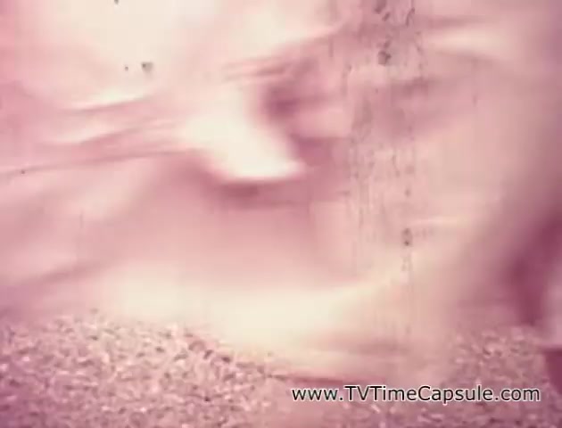 The still from the 'Lady Scott' commercials features soft, blurred visuals, likely showcasing the flow of tissue or paper towels. The colors appear muted, suggesting a focus on gentle aesthetics and patterns. The setting implies a light and airy atmosphere, aligning with the promotional intent of highlighting the softness and quality of Scott Paper Company's products. The overall effect is evocative of a nostalgic, vintage presentation style typical of mid-20th century commercials.