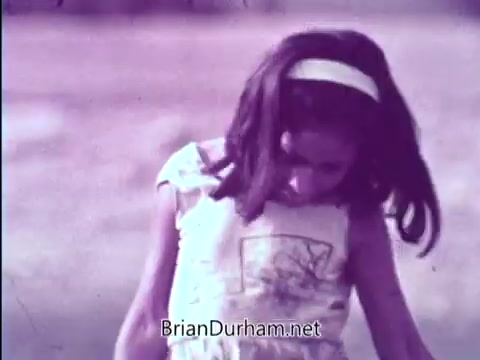 The still is from a 1967 PSA featuring the Smothers Brothers, promoting the Foster Parents Plan. It shows a young girl looking down, likely conveying a sense of contemplation or sadness. The brothers emphasize the importance of financially adopting a hungry overseas child for just 50 cents a day, highlighting the initiative's altruistic goal. The tone aims to inspire viewers to get involved and make a difference.