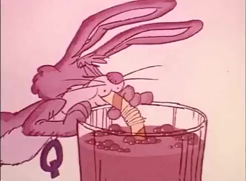 The still from the 1970s/1980s Nesquik commercial features the animated Quik Bunny enjoying a drink. The bunny, depicted with large ears and a playful expression, is holding a carrot while leaning over a glass filled with brown liquid and bubbles. It prominently wears a red collar adorned with a large 'Q,' emphasizing its association with Nesquik. The background is pastel pink, enhancing the whimsical nature of the advertisement.