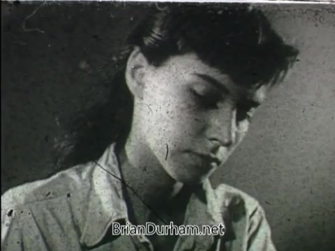 The still from the YWCA public service announcement depicts a young woman with a serious expression, looking down, suggesting a theme of introspection or concern. The black-and-white aesthetic and texture indicate it’s an older film, likely emphasizing the YWCA's message about women's issues or community support. The context implies it relates to the organization's mission of empowering women and promoting social justice.
