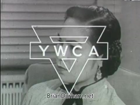 The still from the YWCA public service announcement features a woman with a thoughtful expression, positioned in front of a window with blinds. The YWCA logo is prominently displayed in the center. The visual suggests a focus on women’s issues and advocacy, typical of YWCA messaging. The date is unspecified, but the aesthetic indicates a historical context, likely mid-20th century.