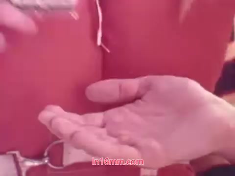 The still from the 1970s Dentyne Dynamints commercial shows a close-up of a hand reaching to take a mint. The background appears to be bright and colorful, indicative of the vibrant advertising style of the era. The focus on the hand emphasizes the act of sharing or enjoying the product, capturing the excitement and appeal of the candy. The overall aesthetic reflects the playful and energetic vibe typical of 1970s commercials.