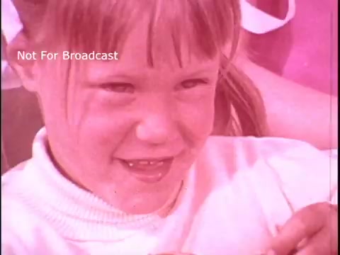 The still shows a young girl smiling, possibly engaged in a joyful moment. She has light brown hair and is wearing a light-colored sweater. The background is slightly blurred, suggesting a playful or homey setting, likely emphasizing the convenience or fun of using Baggies food storage bags. The image has a nostalgic, vintage quality typical of older commercials.