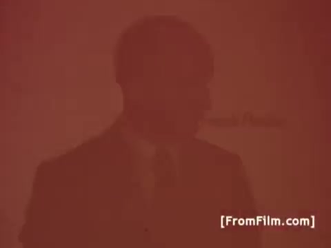 The still from the 16mm print of 'Perdue Chicken Commercials - 1970's' features Frank Perdue, the founder of Perdue Farms. He is dressed in a suit, likely delivering his signature tagline: 'It takes a tough man to grow a tender chicken.' The color tone appears faded, typical of vintage film prints from that era.
