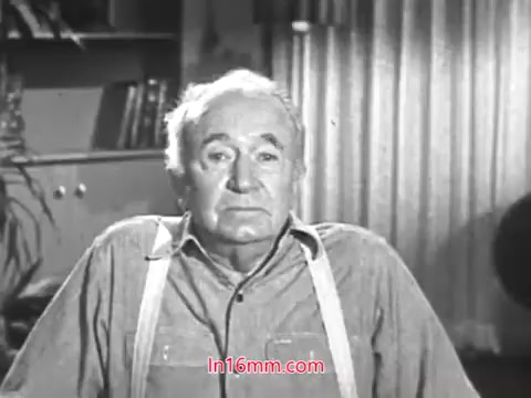 The still features Walter Brennan sitting down and speaking directly to the audience. He appears earnest and sincere, dressed in a simple button-up shirt with suspenders. The background includes soft furnishings and curtains, contributing to a warm, homey atmosphere. The context suggests he is discussing the importance and tradition of Christmas Seals, emphasizing their longstanding significance in his family's holiday celebrations.