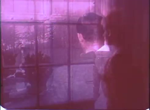 The still from 'A Reflection of Fear' trailer displays a haunting atmosphere typical of low-budget horror films. It features a ghostly overlay of figures, suggesting tension and mystery. The characters appear to be gazing out a window, possibly caught in a moment of contemplation or fear, while the soft focus and muted colors enhance the eerie vibe. The visual suggests themes of emotional turmoil and suspense central to the film's narrative.