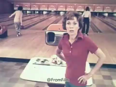 The still likely captures a scene from the famous Rolaids commercial featuring the well-known tagline 'How do you spell relief? R-O-L-A-I-D-S.' Set in a bowling alley, the focus is on a woman looking surprised or concerned, possibly experiencing discomfort while friends bowl in the background. This humorous setup connects the product with the idea of relief from discomfort, reflecting the ad's lighthearted approach. The commercial's success also led to Rolaids sponsoring the Rolaids Relief Man of the Year Award in MLB, emphasizing its association with relief and comfort.