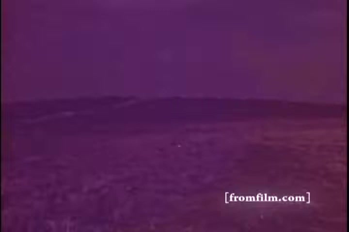 The still depicts a vast, open landscape with rolling hills or fields under a muted, purple-toned sky. The colors suggest a vintage or altered film quality, typical of a 16mm print, evoking a sense of nostalgia or historical context. The scene likely aims to convey a serious or reflective mood, fitting for a public service announcement about an emergency fund.