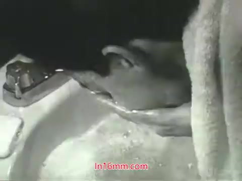 The still from the PSA features a person leaning over a sink, washing their face with water. The scene is monochromatic, fitting the era of the 1960s. This visual aligns with Mason Adams's voiceover about urban air pollution and emphasizes the idea of cleanliness, contrasting the ability to wash away dirt with the inability to cleanse one's lungs from polluted air. The message encourages viewers to take action regarding air quality.