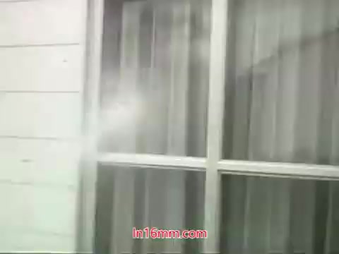 The still from the PSA features a close-up of a window with sheer curtains, highlighting the contrast between the clean indoor environment and the polluted outdoor air referenced in Mason Adams' voiceover. The shot captures the idea of urban pollution and emphasizes the message of the importance of clean air. The curtains suggest a barrier between the polluted outside and a healthier indoor space, reinforcing the PSA's theme that while many items can be washed, our lungs cannot be cleaned in the same way. This visual contributes to the urgent call for action to address air quality issues in urban areas.