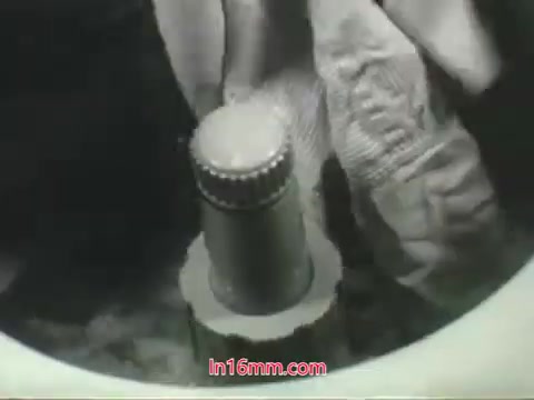 The still from the 'Clean Air Public Health Service PSA' features a close-up of a person's gloved hand interacting with a washing machine or similar appliance. The focus is on a metal component, possibly a lid or knob, suggesting the act of cleaning. The imagery aligns with Mason Adams' voiceover highlighting the importance of air quality in urban settings and the notion that, unlike objects that can be washed, our lungs cannot be cleaned in the same manner. This visual reinforces the message about the consequences of air pollution.