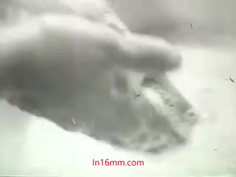 The 16mm still from the 'Clean Air Public Health Service PSA' features a close-up of a hand washing an object, likely to symbolize the act of cleaning contaminants. The imagery aligns with the voiceover by Mason Adams, which emphasizes the inability to wash one's lungs of pollution, highlighting the importance of air quality. The visual underscores the contrast between the physical act of cleaning and the abstract notion of polluted air, aiming to provoke thought about public health and environmental issues in urban areas during the 1960s.