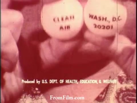 The still from the 1964 Pollution PSA features a person holding two eggs marked 'CLEAN AIR' and 'WASHINGTON, D.C. 20201.' The image emphasizes the importance of clean air and addresses environmental concerns related to pollution. The print is produced by the U.S. Department of Health, Education, and Welfare, highlighting governmental efforts to raise awareness about air quality issues.