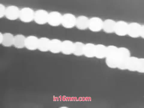 The still from the 1960s commercial for Leg Street panty hose features a blurred background with bright, circular bokeh lights creating a dynamic and stylish atmosphere. The focus is on conveying a sense of glamour and fashion associated with the panty hose. The accompanying jingle emphasizes convenience, fit, and affordability, presenting Leg Street as the go-to destination for stylish legwear.