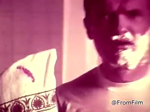 The still from the 'Tide XK' laundry detergent commercial features a man with a concerned expression, holding a guest towel that has a visible bloodstain. He has shaving cream on his face, indicating he's in the bathroom, possibly caught off guard by the stain. The overall theme emphasizes the effectiveness of Tide XK in removing tough stains, highlighting the breaking of traditional stain barriers. A voiceover mentions overcoming blood and ketchup stains, showcasing Tide XK as a revolutionary cleaning solution.