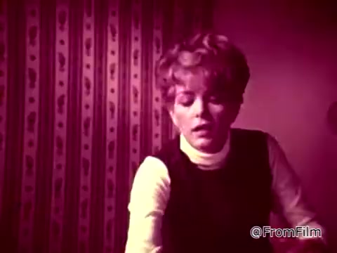In this still from the 'Tide XK' commercial, a woman appears concerned as she reacts to a stain situation. The background features patterned wallpaper, and the lighting creates a dramatic ambiance. The voiceover emphasizes the innovative cleaning power of Tide XK, claiming to break through tough stains like blood and ketchup, indicating a major advancement in laundry detergents. Overall, the scene captures a moment of tension related to household cleaning challenges.