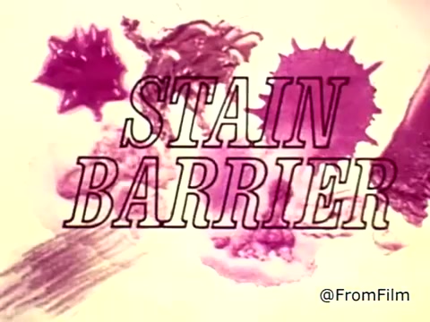 The still from the Tide XK laundry detergent commercial features bold text stating 'STAIN BARRIER' over colorful splotches resembling blood and ketchup stains. The visual emphasizes the product's ability to tackle tough stains, highlighted by a voiceover that mentions breaking the barriers of stain removal. The message conveys confidence in Tide XK's cleaning power, portraying it as a revolutionary detergent.