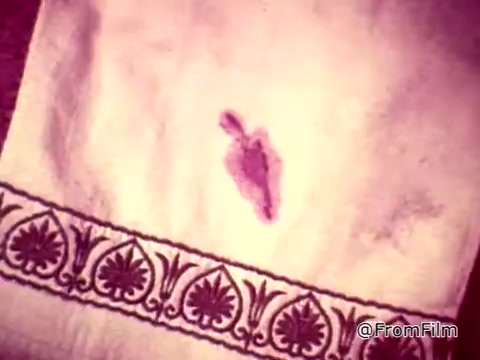 The still features a close-up of a white guest towel with a noticeable ketchup stain, illustrating a dramatic moment in a Tide XK laundry detergent commercial. The visual emphasizes the theme of stain removal challenges, highlighted by the narration referring to both blood and ketchup stains. The text suggests a breakthrough in cleaning technology, branding Tide XK as a powerful solution for challenging stains. The towel's ornate border contrasts with the blemish, enhancing the focus on the stain's visibility.