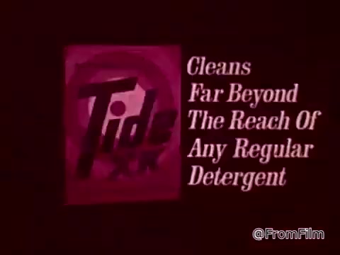 The still features the Tide XK logo prominently, set against a deep red background. The text emphasizes its superior cleaning power, stating it 'Cleans Far Beyond The Reach Of Any Regular Detergent.' The context hints at tackling tough stains, like blood and ketchup, highlighting a breakthrough in cleaning technology. The commercial likely champions Tide XK as an advanced solution for laundry challenges.