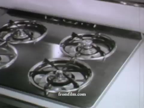 The 16mm still from 'UPA Commercials - late 1950's' features a close-up view of a stainless steel gas stove with four burners. The stove is shown against a minimalistic kitchen background, typical of mid-century design. The commercial likely emphasizes modern appliances, showcasing the sleek design and functionality of the stove. UPA's animation style often blended humor and visual appeal, suggesting the ad may also have a creative or engaging narrative.