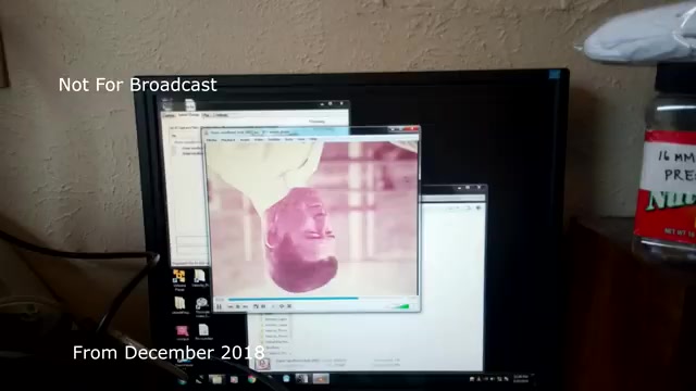The still shows a computer monitor displaying an upside-down video playback from a 16mm film transfer, specifically from the Chase and Sandborn commercial. The video window is partially obscured by other open applications, and there's a hint of an audio sync issue present. The image is labeled 'Not For Broadcast' and notes that it's from December 2018, reflecting an archival moment that was never shared before, possibly due to the mentioned technical difficulties. The surroundings of the monitor indicate a casual workspace setup.