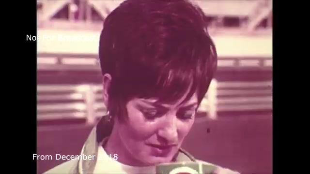 The still from the 'December 2018 transfer talk Chase and Sandborn Commercial' features a woman with short hair, seemingly engaged in a moment of reflection or concentration as she holds a can. The colors are somewhat muted, typical of 16mm film, giving a vintage feel. The background appears blurred, focusing attention on her expression, which conveys seriousness or contemplation. This clip reflects on the technical process of transferring film to video, likely discussing the complexities involved, particularly with audio synchronization challenges. The watermark indicates it’s not meant for broadcast, emphasizing its archival nature.