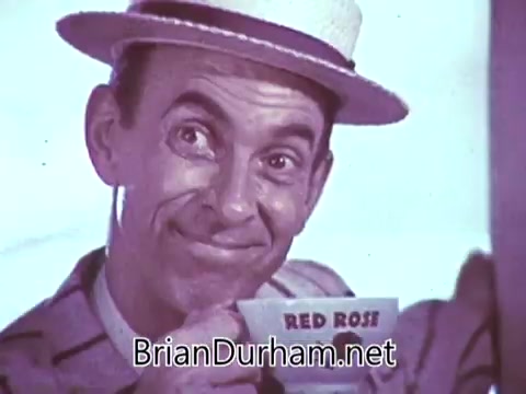 The still from the 1968 'Another Red Rose Tea' commercial features a man wearing a straw hat and a striped shirt. He is smiling and holding a cup with the brand name 'RED ROSE' clearly visible. The overall tone suggests a lighthearted and cheerful atmosphere, typical of advertisements from that era, promoting the enjoyment of tea. The vibrant colors and the man's expression convey a sense of warmth and friendliness associated with the product.