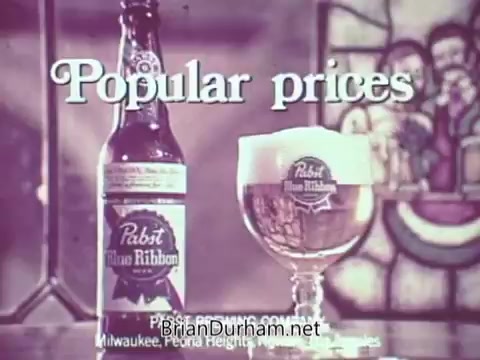 The still features a Pabst Blue Ribbon beer bottle and a glass of beer, both prominently displayed. The background includes a stained glass element, enhancing the commercial's aesthetic. The text 'Popular prices' appears in bold, suggesting a focus on affordability. The overall vibe conveys a sense of accessibility and enjoyment associated with the brand.
