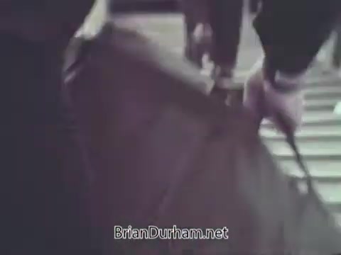 The still from the 1968 US Navy PSA depicts a close-up of individuals handling luggage or equipment, likely in a military context. The focus is on hands actively engaged in the task, emphasizing preparation and movement, which reflects the organized and disciplined nature of Navy operations. The atmosphere suggests urgency or readiness, common themes in public service announcements aimed at promoting recruitment or awareness.