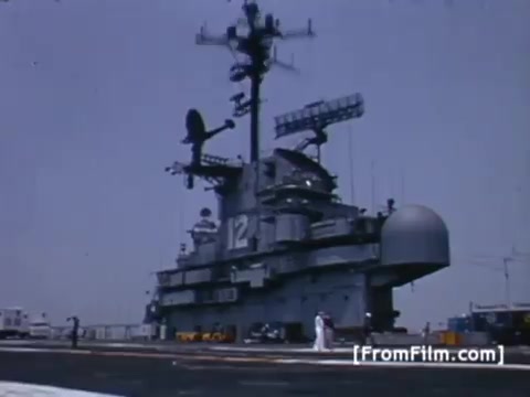 The still shows the USS Hornet, an aircraft carrier, prominently displayed against a clear blue sky. Various antennas and structures are visible on its deck, highlighting its technological capabilities. The context involves preparation by Western Union International to send satellite images of the Apollo 11 recovery operation, showcasing the ship's role in a significant historic event.