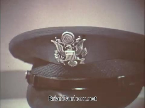 The still features a close-up of a U.S. Air Force officer's hat, prominently displaying the insignia. This image is part of a 1960s recruiting PSA targeting doctors to join the Air Force Reserve during the Vietnam War era. The focus on the hat symbolizes military service and highlights the need for medical professionals. The overall tone may convey a mix of patriotism and the unique niche of recruiting specialized healthcare providers for military service.