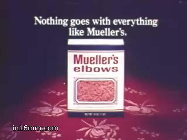 The still features a box of Mueller's elbows pasta prominently displayed against a patterned tablecloth. The text reads, 'Nothing goes with everything like Mueller's,' emphasizing the versatility of the product. The visual is indicative of advertising style typical of the 1970s, using straightforward messaging and vibrant colors to grab attention.