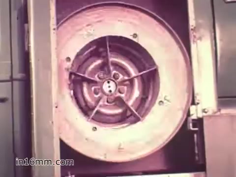 The 16mm still from the US Army recruiting PSA 'Your Man in Nürnberg' depicts a close-up view of a component, likely part of military machinery or equipment. The focus is on a circular fan or rotor assembly, showcasing intricate details like blades and central components. This imagery connects to the narrative of Joe Naifus, emphasizing the technical and logistical skills acquired in the Army, underlining the complexity and importance of his role in keeping military operations running smoothly. The visual reinforces the theme of efficiency and competence in Army service while balancing professional duties with personal exploration in Nuremberg.