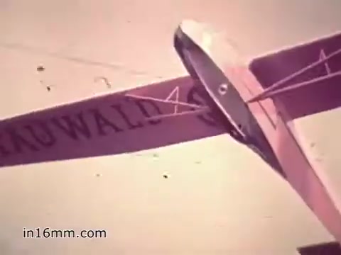 The still from the US Army recruiting PSA 'Your Man in Nürnberg' features a model airplane, likely symbolizing the precision and technical skills required in military aviation and logistics. The airplane's pink color and labeling add a personalized touch, while the context highlights Joe Naifus, a Specialist Four in the U.S. Army, managing complex supply duties. This image aligns with the narrative of the film, showcasing the practical training and responsibilities military personnel undertake, blending professional life with leisure activities in Nuremberg.