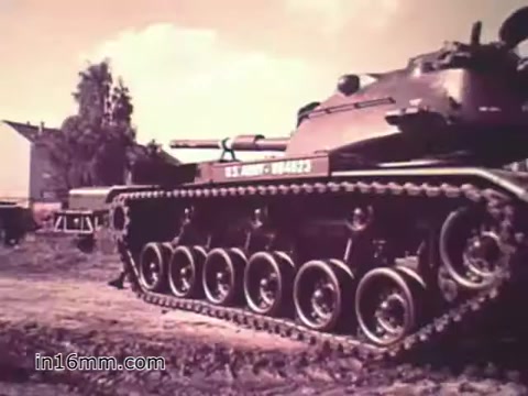 The 16mm still from 'Your Man in Nürnberg' features a tank, showcasing its tracks and armored body. The scene underscores the technical and logistical challenges of military supply management, with a focus on Specialist Joe Naifus's role in maintaining the vehicle. The background includes light vegetation and structures, indicating a military or training environment. The colors appear warm, characteristic of 1960s film, adding a nostalgic tone to the PSA promoting Army careers.