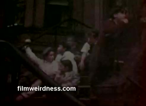 This 16mm still from Barney's 1970 commercial features children sitting on stoops, capturing a nostalgic urban scene. The image has undergone color correction to enhance its vibrancy, improving the original film quality. The commercial received a CLIO award, recognizing its impact.