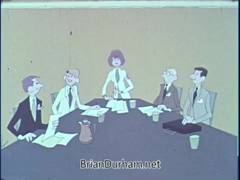 The still depicts a group of five animated characters seated around a conference table in a meeting setting. They appear to be discussing topics related to diet and nutrition, likely in the context of the American Dietetic Association's public service announcement from 1969. The characters are dressed in professional attire, and the background features a simple, solid color.