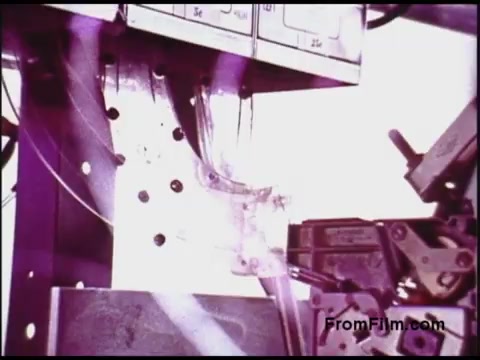 The still from the 1970s Bell System film showcases a technical setup, likely related to telecommunications or industrial machinery. It features mechanical components, including various connectors and wires, in a close-up shot that emphasizes the intricate workings of the equipment. The image has a vintage quality, with a palette that may include muted colors, typical of film from that era.