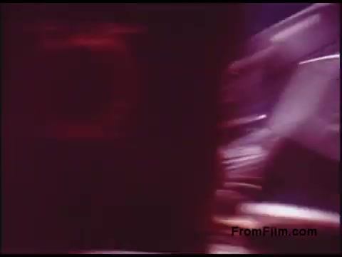 The still from the 'Bell System Film from the 1970s' features a somewhat abstract and blurred composition, likely capturing a dynamic moment during filming or editing. The colors appear warm with reds and subtle shades, indicating a vintage aesthetic typical of the era. The scene suggests movement, possibly showing equipment or personnel in a telecommunications context, reflective of Bell System's interest in technology and innovation during that time.