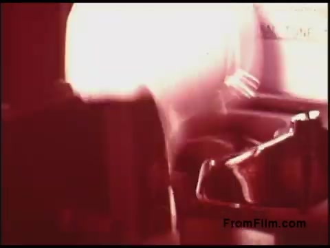 The still from the 'Bell System Film from the 1970s' features a blurred motion effect, conveying a sense of action or activity. The predominant colors are warm, leaning towards red, suggesting a vintage aesthetic. Elements appear to include machinery or equipment, possibly related to telecommunications, reflecting the film's industrial context. Overall, the image captures a dynamic moment indicative of the era's focus on technology.