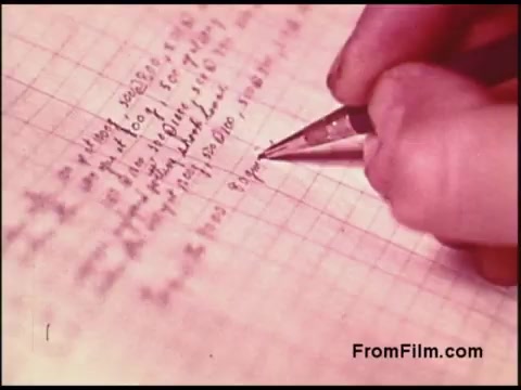 The still from the 16mm 'Bell System Film from the 1970s' depicts a close-up of a hand holding a pen, writing on a piece of grid-ruled paper. The text appears to be in cursive and includes mathematical or technical annotations, suggesting a focus on detailed record-keeping or documentation. The warm color tone gives it a vintage feel, characteristic of films from that era.