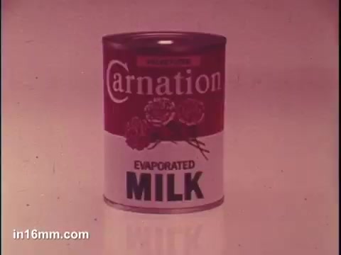 The still features a can of Carnation Evaporated Milk, prominently displaying the brand name 'Carnation' at the top. The can's design includes illustrations of carnations and bold text reading 'EVAPORATED MILK.' The background is likely simple, focusing attention on the product itself, which is part of a commercial aimed at showcasing its use in sauces. The overall aesthetic is typical of mid-20th century advertising.