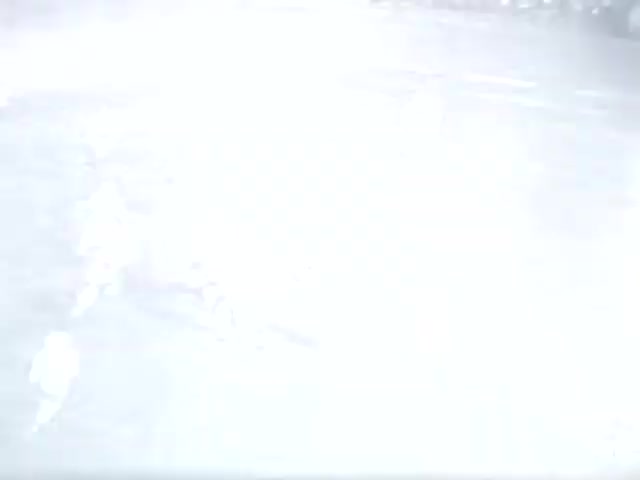 The still from 'High School Football - 1961 (2) [FF0005]' depicts a football scene, likely during a game. The image is bright and somewhat washed out, which may obscure details. Players are likely in action, with some movement visible. The context suggests it is a high school match, but specific teams or location remain unknown.