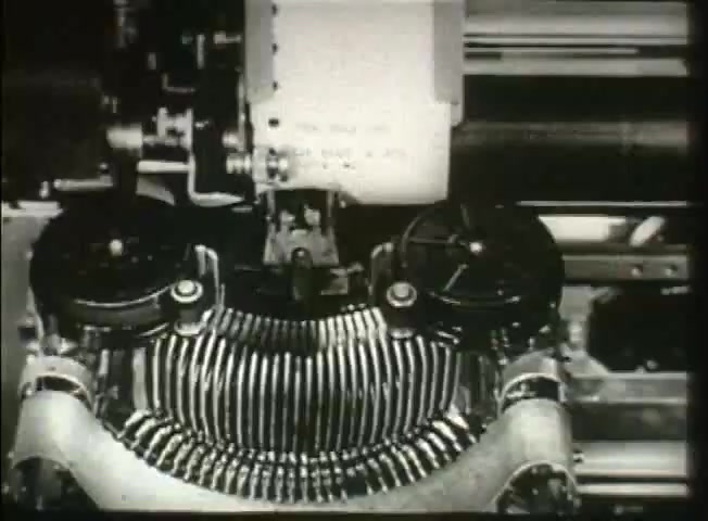 The still from 'Story Without End' features a close-up of a typewriter, focusing on its mechanical components. The image captures the typewriter's hammers and keys in action, with a sheet of paper emerging from the machine, suggesting the process of documentation or communication. This visual likely highlights the technological aspects of the Bell System during the late 1940s, emphasizing the importance of efficient communication methods in the context of the network's operations. The monochrome aesthetic reflects the era's filmmaking style.
