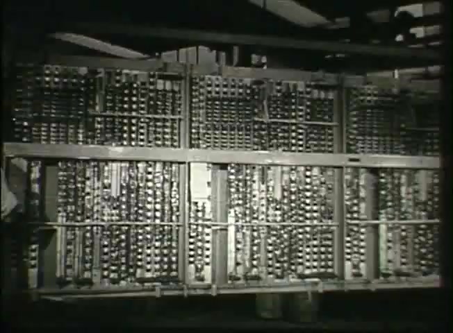 The still from 'Story Without End' features a large, intricate assembly of telephone switching equipment typical of the late 1940s. The frame presents rows of metal connectors and switches, showcasing the technology used in central offices to manage telecommunications. This image highlights the complexity of the Bell System’s network infrastructure during that era, reflecting advancements in communication technology. The monochrome presentation adds a historical context to the film's focus on the evolution of telephone services.