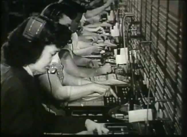The still from 'Story Without End' shows a row of telephone operators in a central office, working at their switchboards. The scene captures women wearing headsets and concentrating as they handle calls, illustrating the manual nature of telecommunications in the late 1940s. This footage reflects the operations of the Bell System, emphasizing the human element in the network's communication processes during that era.