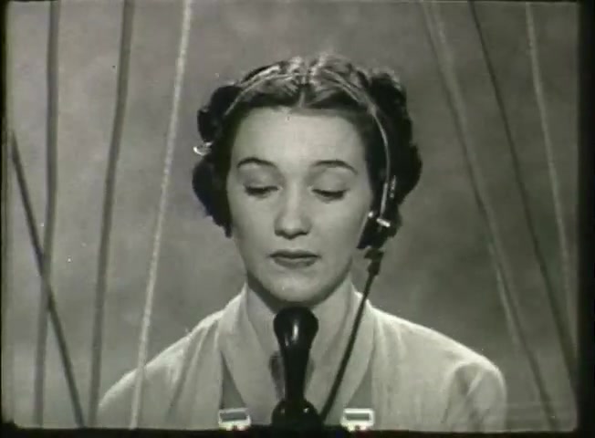 The still from 'Story Without End' features a woman with a vintage hairstyle and a telephone headset, focused on a microphone. Her expression is serious, suggesting she is engaged in communication. The backdrop is simple, emphasizing the central office environment common in late 1940s Bell System films, which often aimed to showcase the technology and personnel behind telecommunication services. The image captures the era's professionalism and the human element of the telephone network.