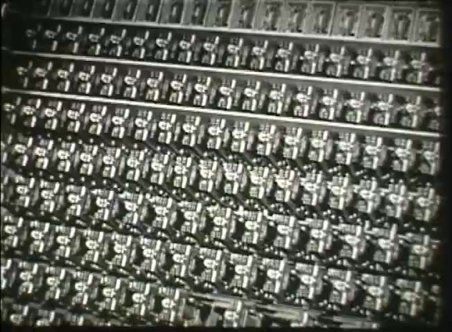 The still from 'Story Without End' likely depicts a close-up view of intricate telephone switching equipment used by the Bell System in the late 1940s. The image showcases numerous mechanical components arranged neatly in rows, highlighting the complexity of the telephone network's infrastructure during that period. This emphasizes the technological advancements and scale of operations within the central office, illustrating the foundation of communication systems at the time.